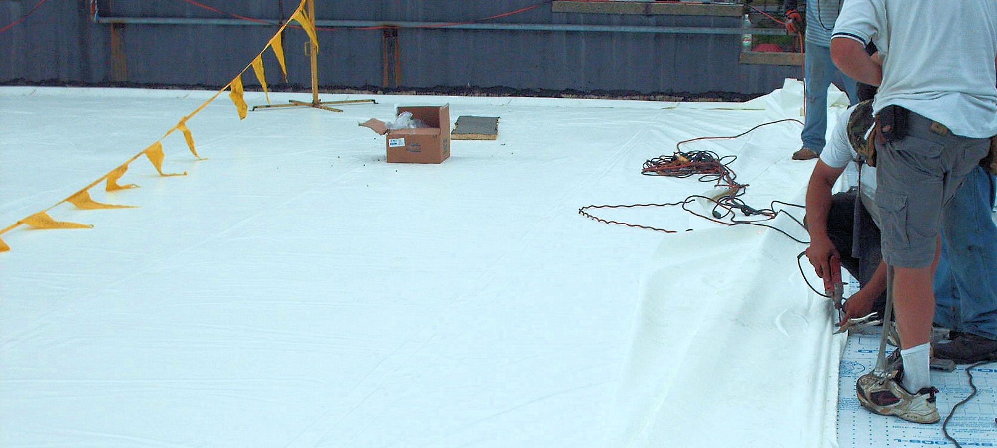 Crew installing a white single-ply membrane on a commercial flat roof