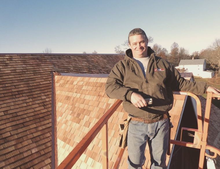 A Frank Stevens and Sons roofer in front of a finished cedar shake roof